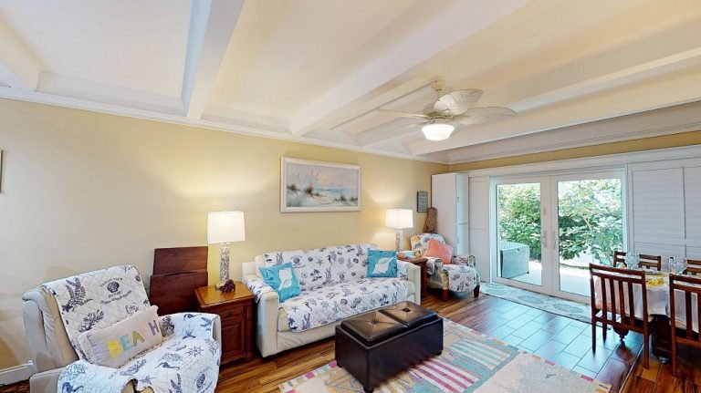Bright living room with sofa and balcony doors at Ocean Club South condo in New Smyrna Beach